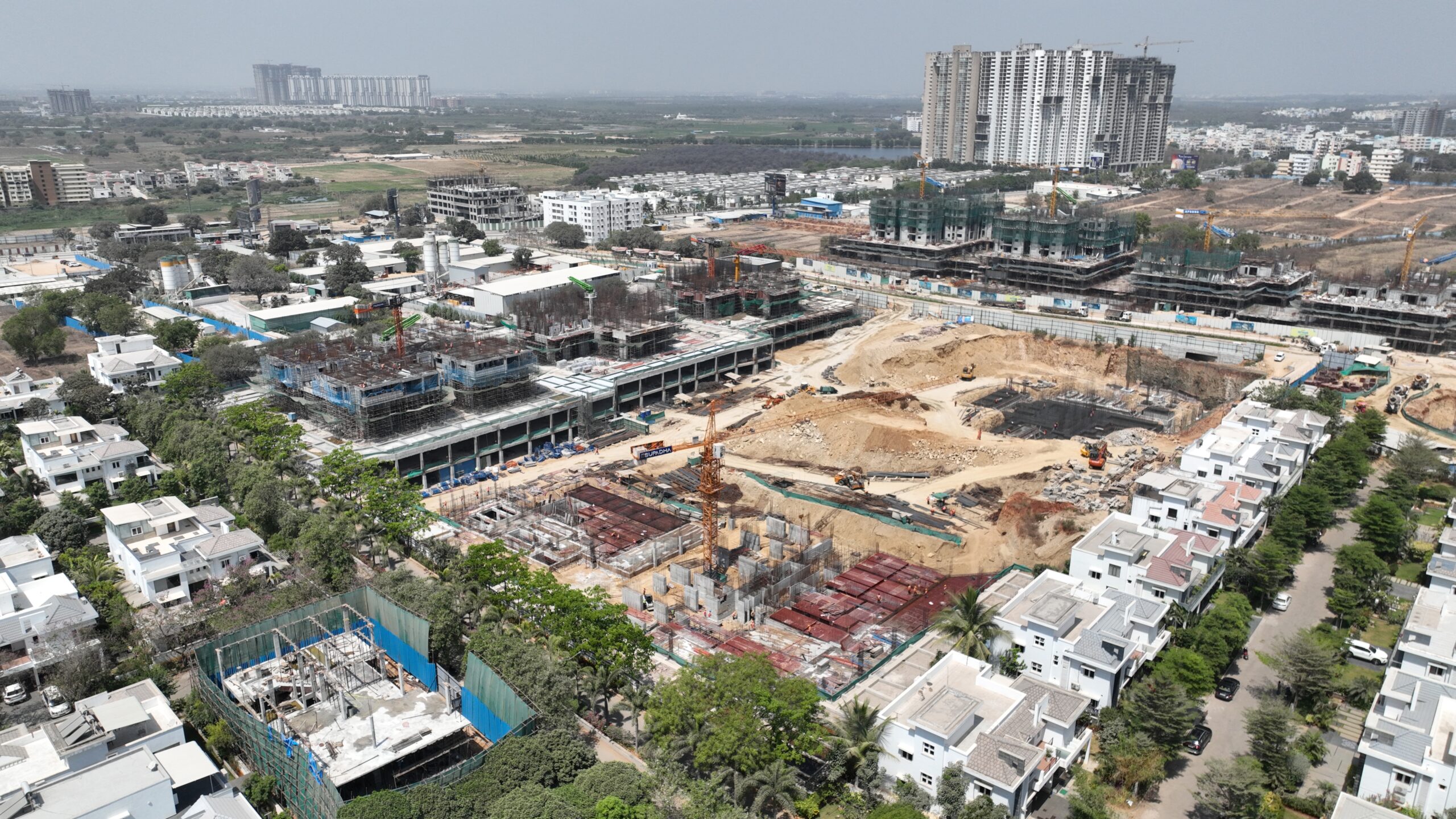 “Wide-angle drone view of Gamya by Supadha project featuring active construction, cranes, and surrounding community”